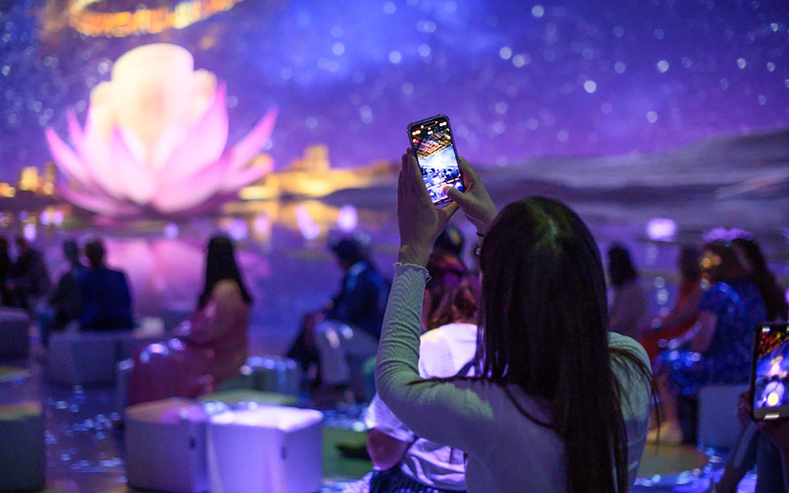 Woman taking a picture of a projection at Tutankhamun Exhibition. 