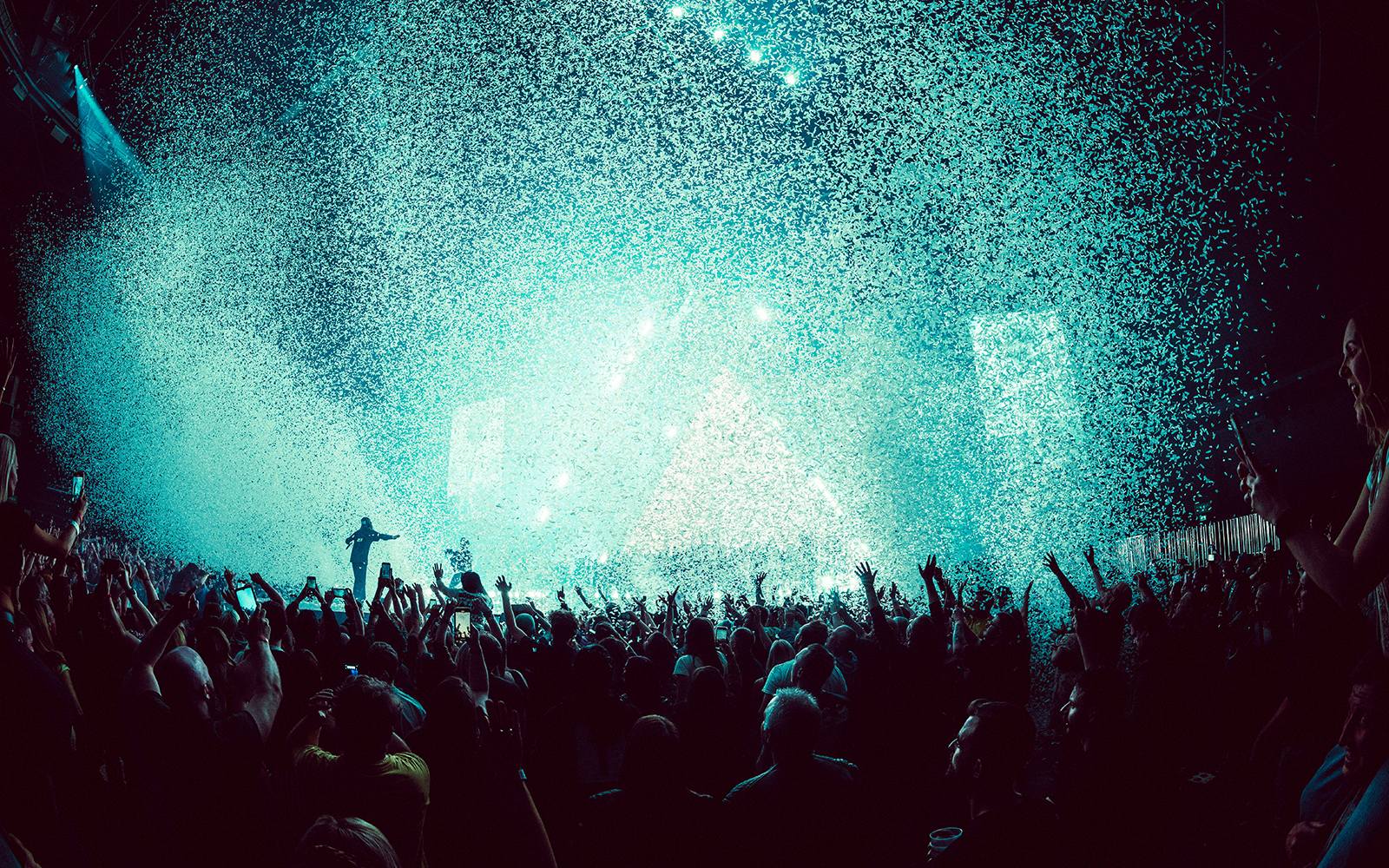 View of the crowd and the stage at a Thirty Seconds to Mars concert, whilst blue confetti is in the air.