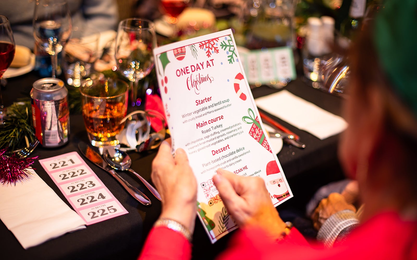 Person reading a food menu at One Day At Christmas. The table is decorated for a Christmas meal.