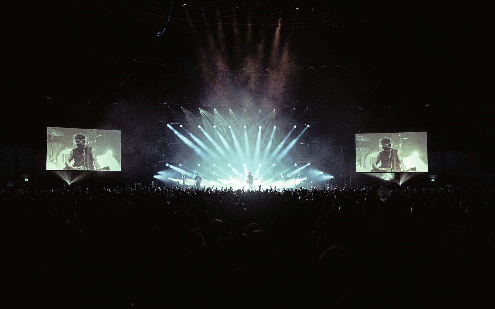 band performing in OVO Hydro with audience's hands in the air