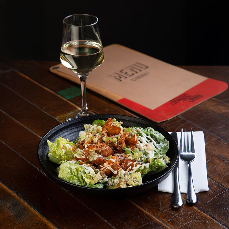 Caesar Salad and glass of white wine on table with Clydebuilt menu.
