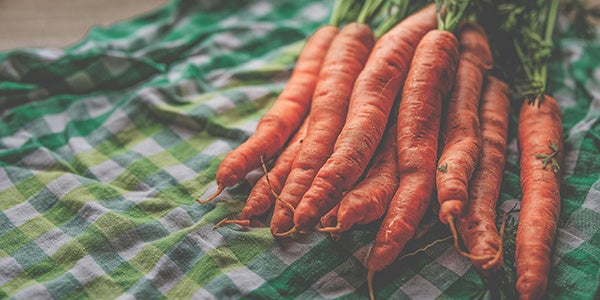 Bunch of carrots on a green checked table cloth.