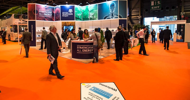 Attendees at an exhibition walking among the different exhibition stands. 