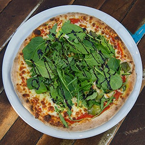 A margherita pizza with salad and glaze on top.