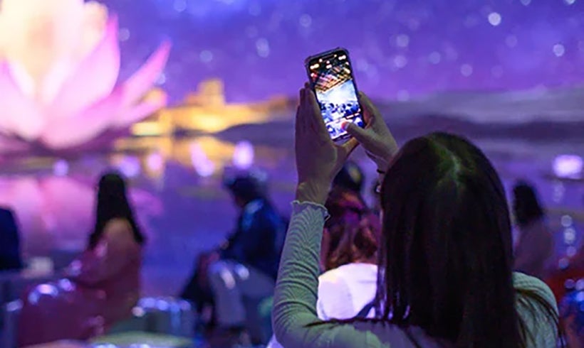 Person taking a picture of a projection at Tutankhamun Exhibition.