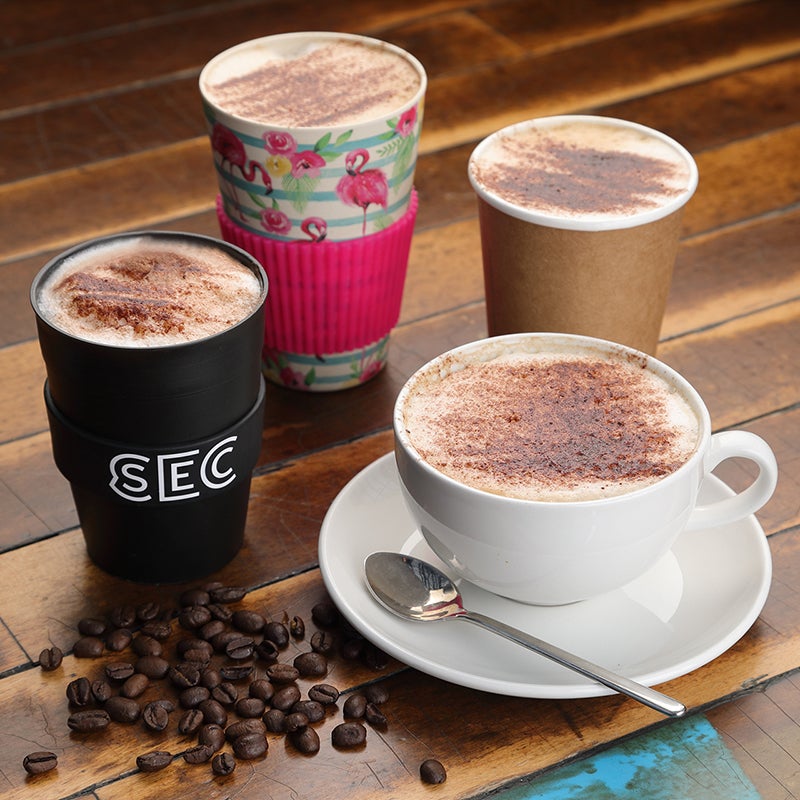 Four coffees on a table with coffee beans sprinkled for decoration.