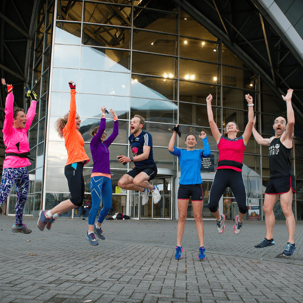 Delegates dressed in running gear jumping in the air outside the SEC Armadillo.
