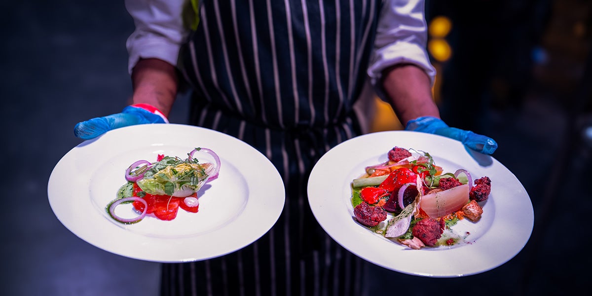 Chef holding two plates of food.