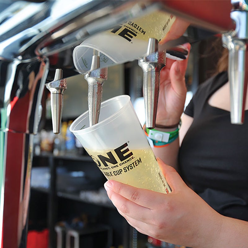 A person pouring beer into a reusable cup.