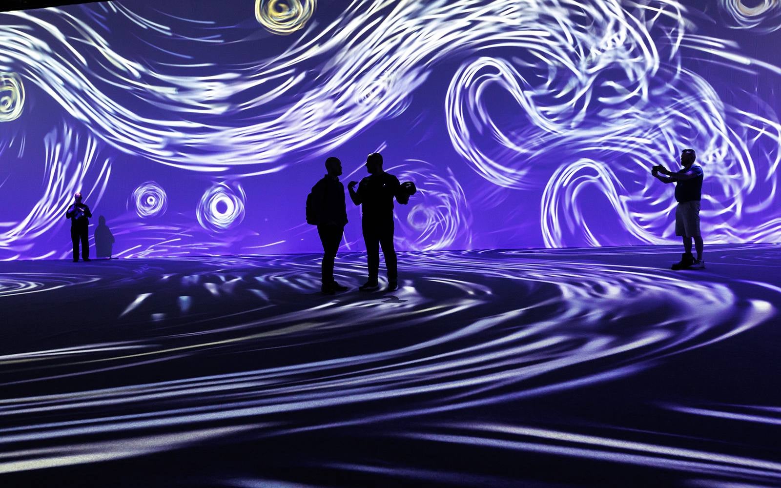 People in front of a purple swirly projection at the Beyond Van Gogh exhibition.