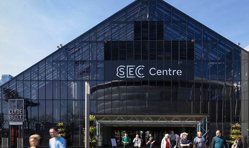 Front view of the SEC Centre, whilst numerous people are walking about.