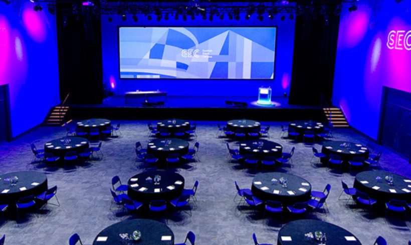 Image of the Loch Suite with tables laid out in cabaret style and a big projection screen on stage