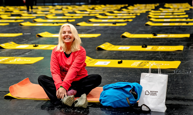 woman sitting on yoga mat surrounded by yellow yogis yoga mats.